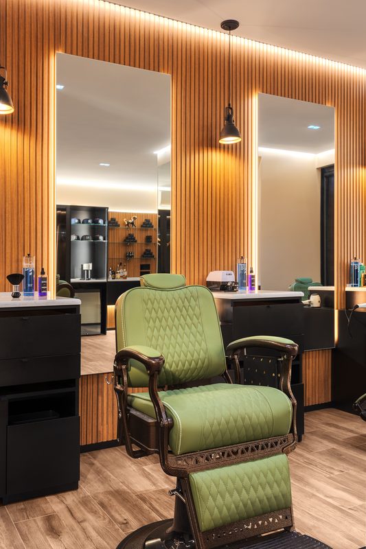 An olive barber chair at a lit mirror inside On the Mark Barber Shop in Williamsburg, Brooklyn
